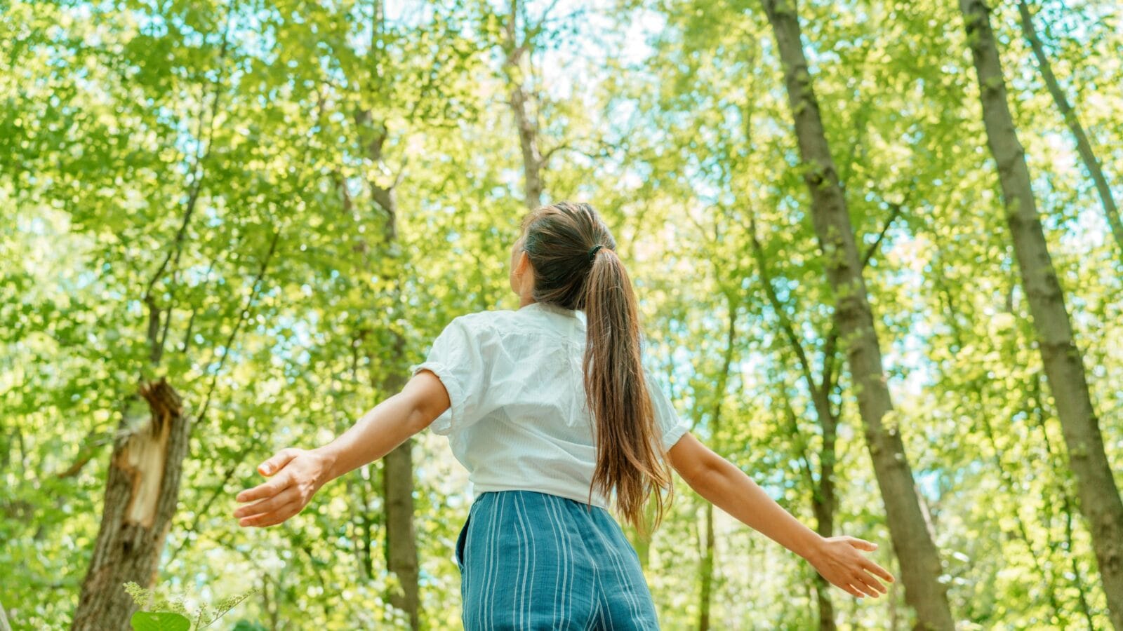 Free woman breathing clean air in nature forest