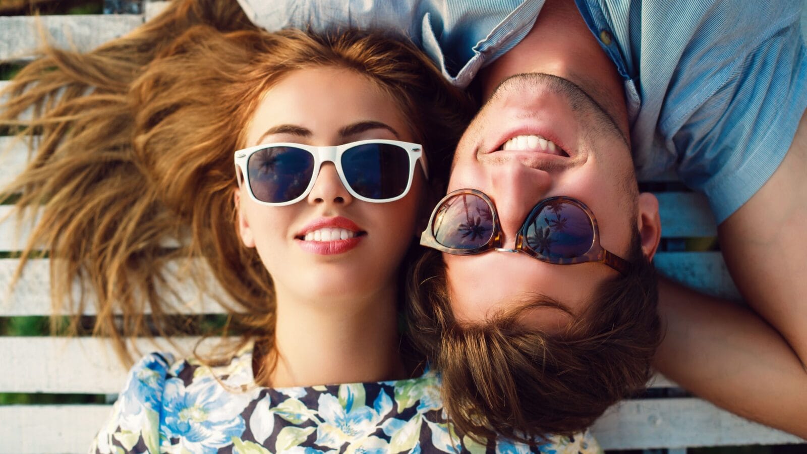 Close up portrait of happy smiling couple in love laying in wood white floor.