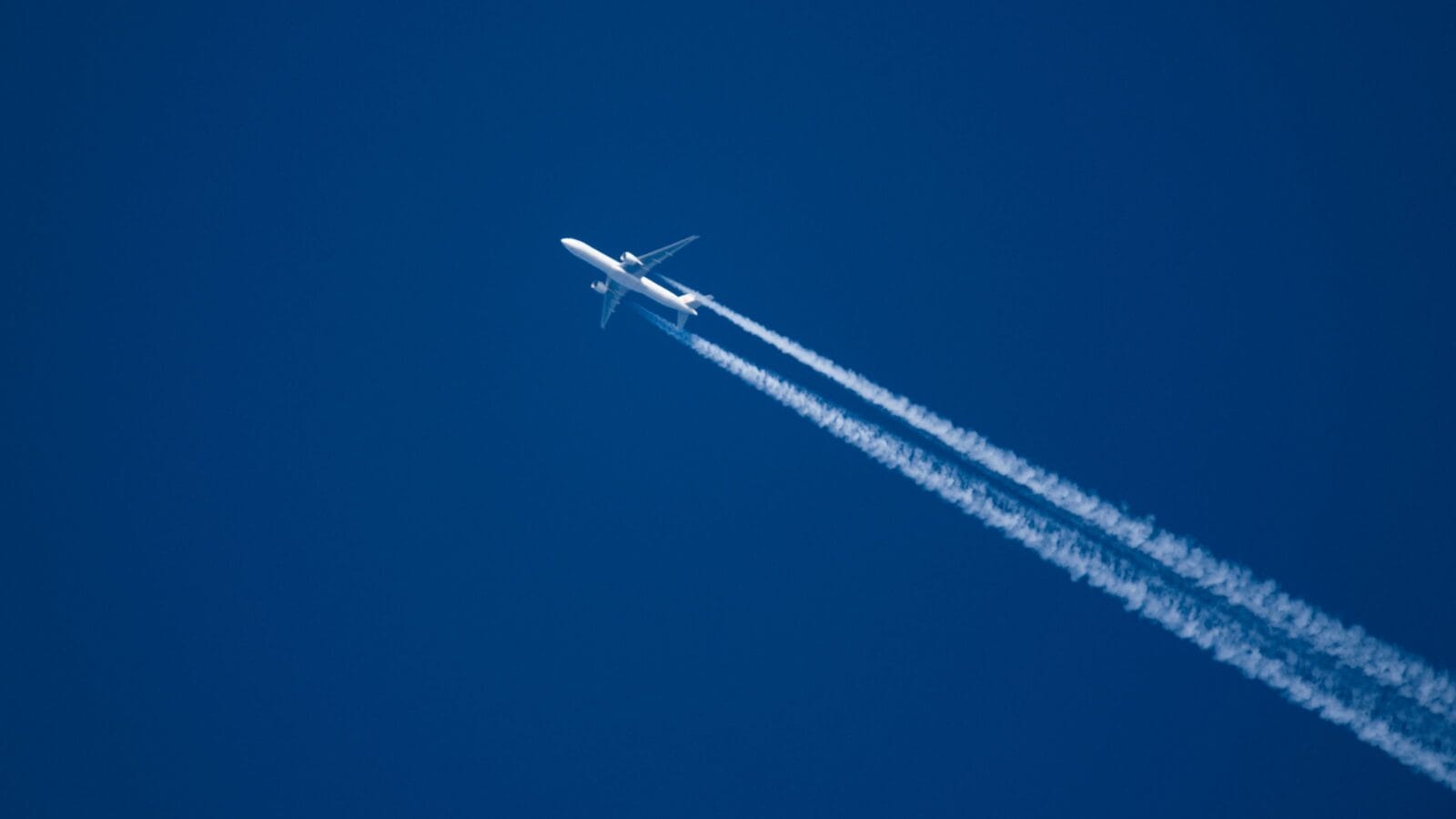 Sharp, telephoto close-up image of jet plane, aircraft with contrails cruising at 35,000 feet Tokyo to NY ground speed 480 knots