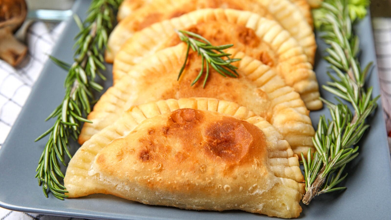 Plate with tasty meat empanadas with rosemary, closeup