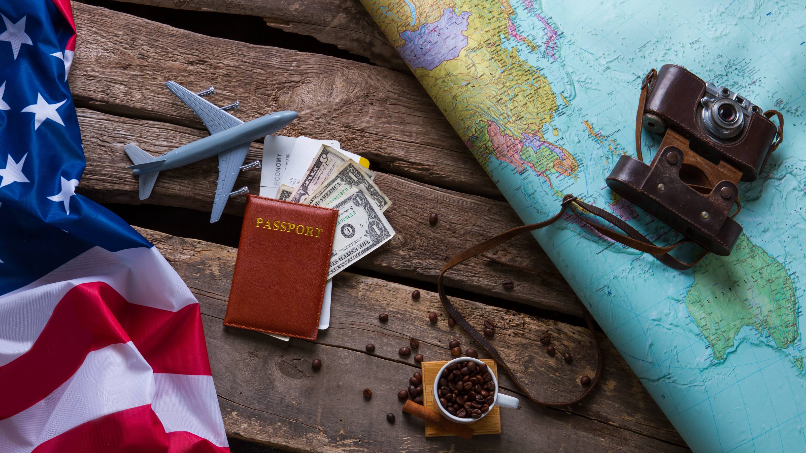 Brown passport and US flag. Photo camera on a map.