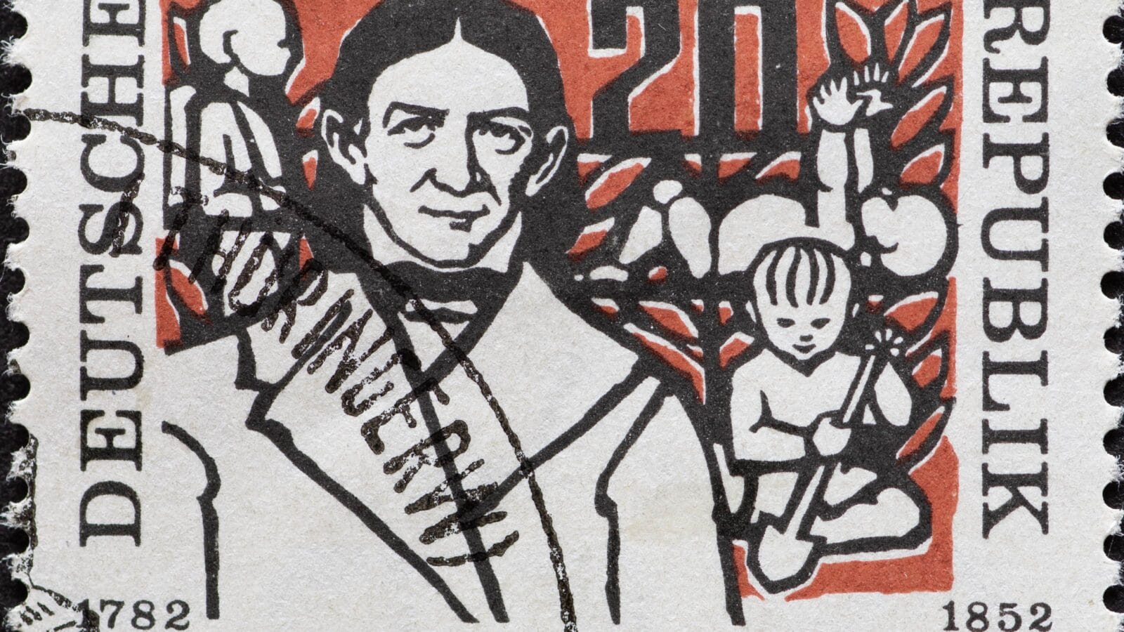 A postage stamp from Germany, GDR showing a portrait of the pedagogue Friedrich Froebel in front of children playing