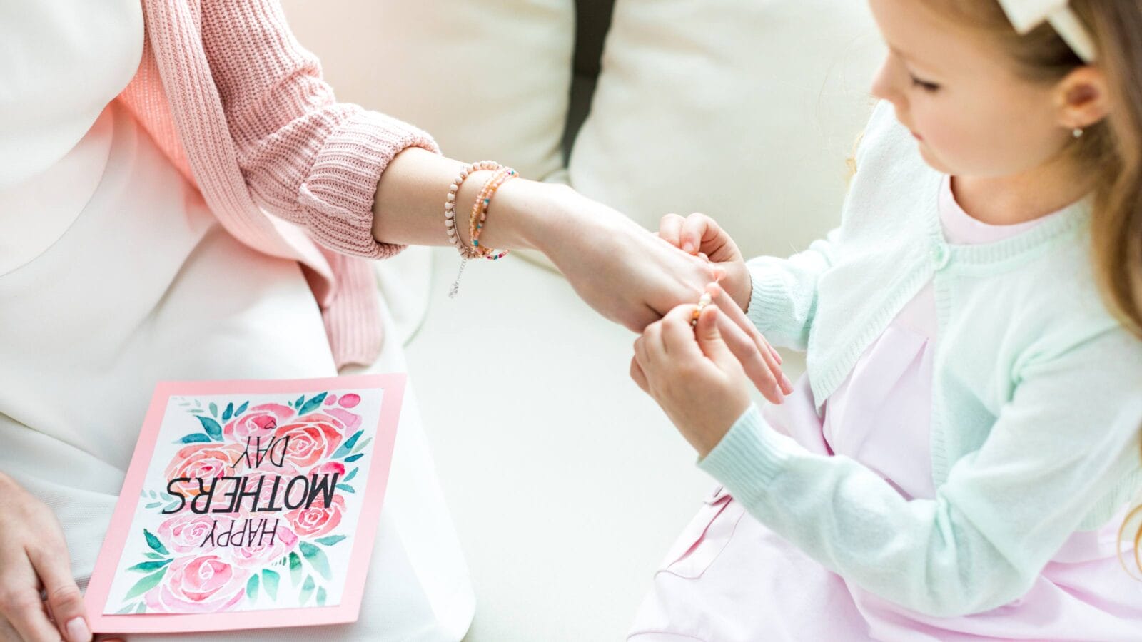 Partial view of cute little girl putting jewelry on hand of her mother on Mothers Day