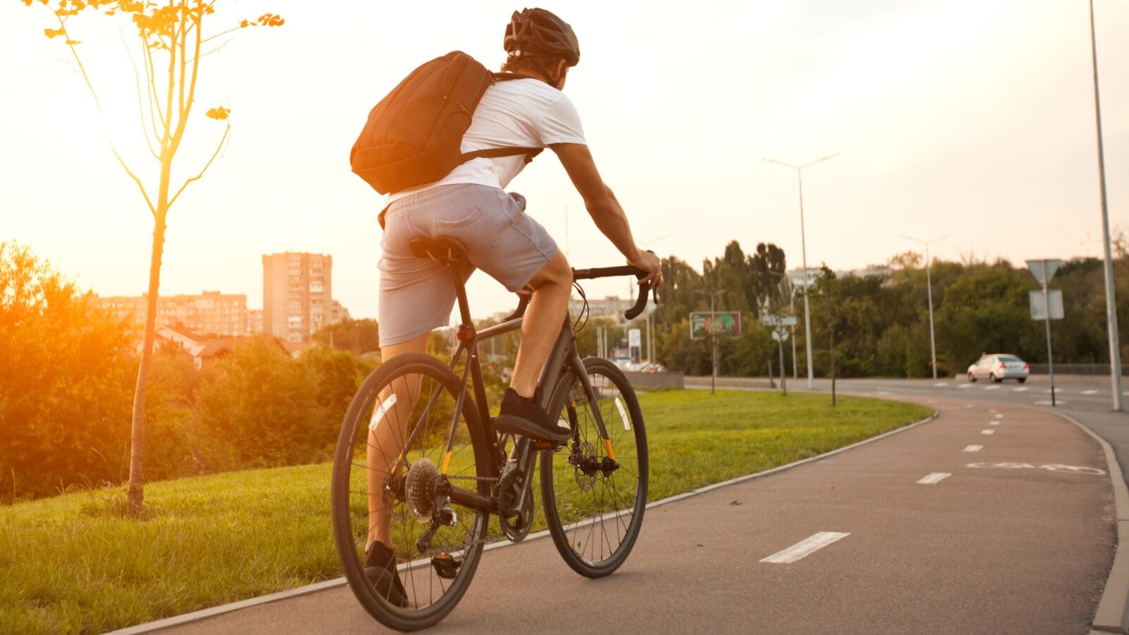 Young guy in casual clothes is cycling on the road in the evening city