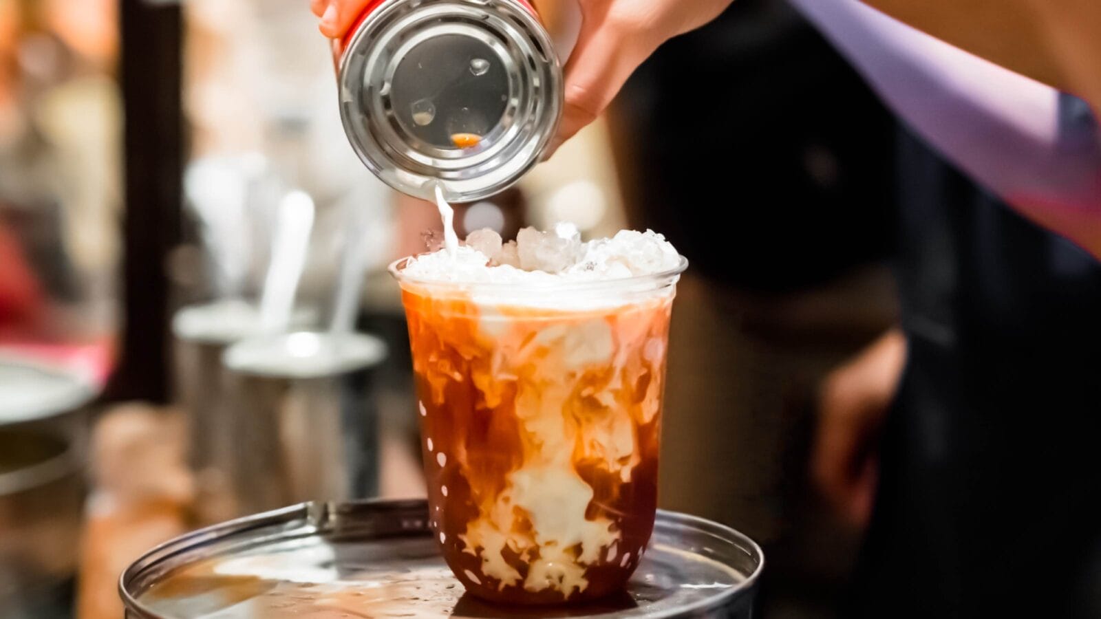 Making iced milk tea, pouring milk from tin can.