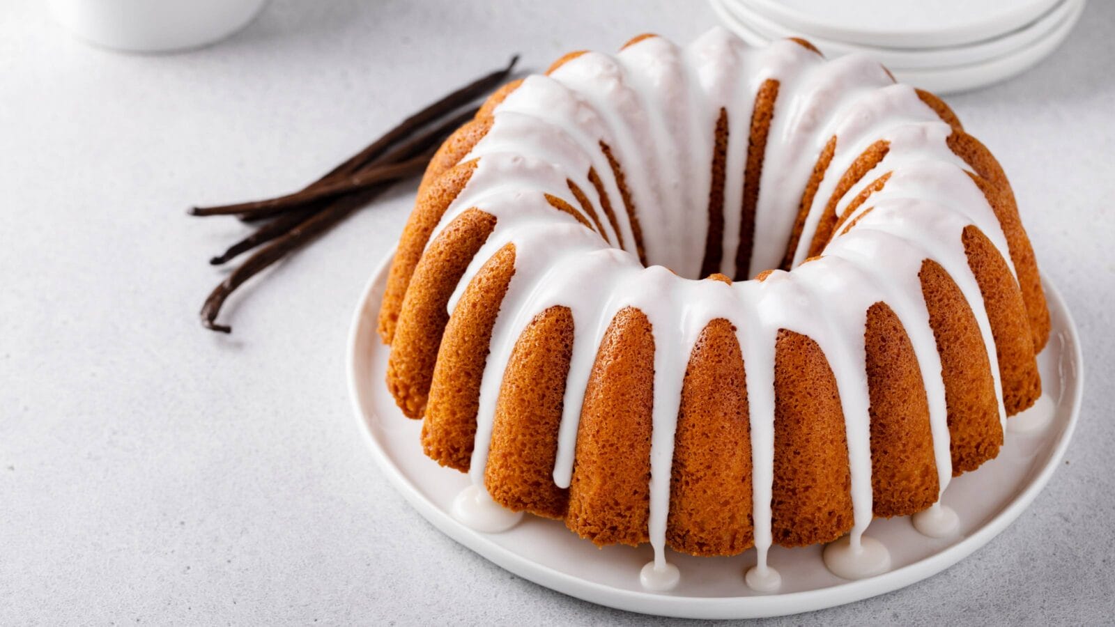 Vanilla bundt cake drizzled with powder sugar glaze with vanilla beans