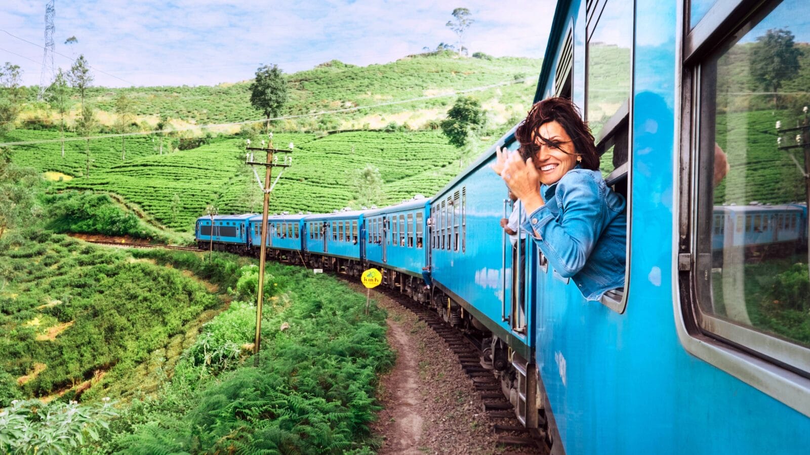 Happy smiling woman looks out from window traveling by train on most picturesque train road in Sri Lanka