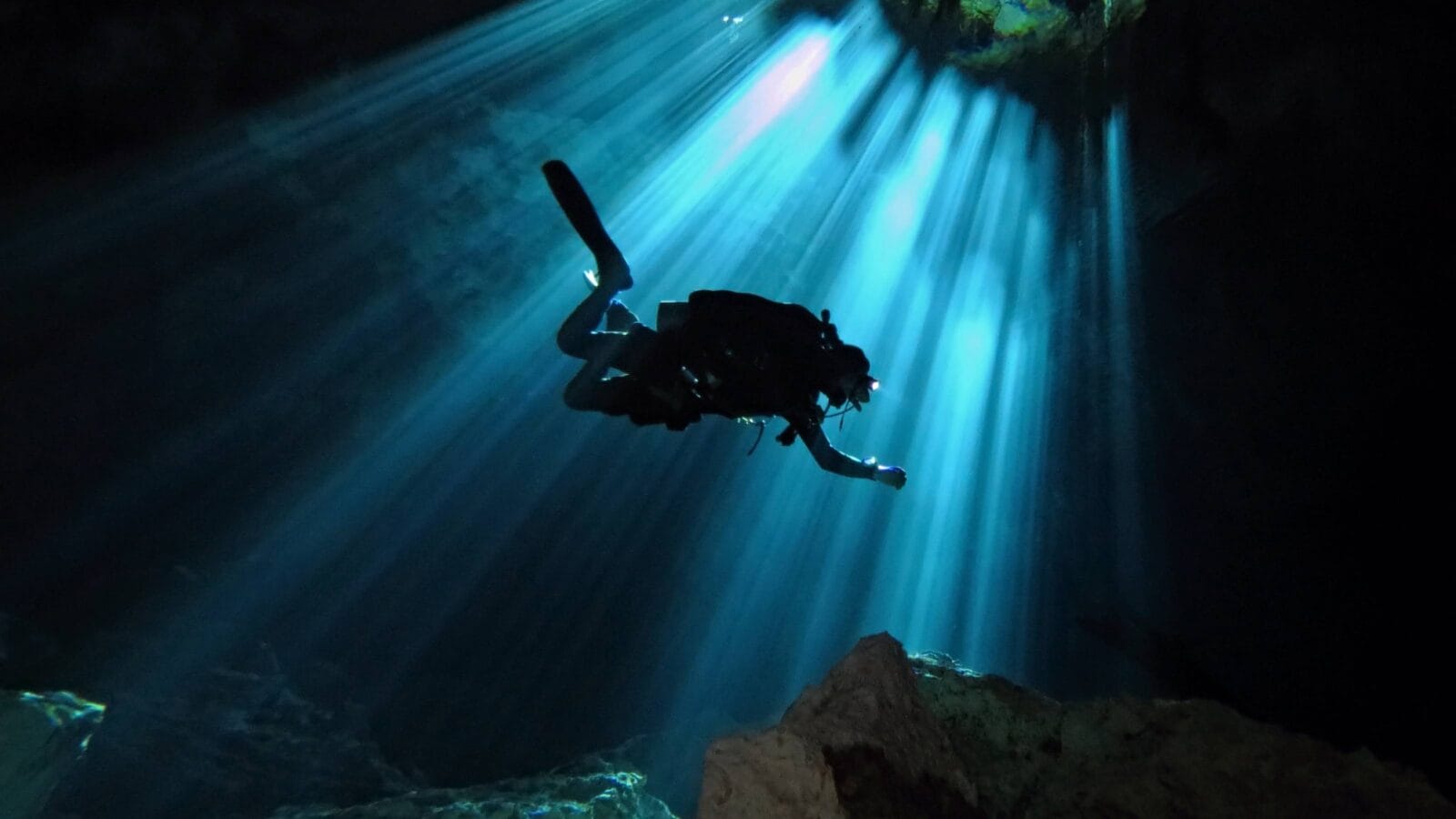 Technical scuba diver exploring underwater cenote.